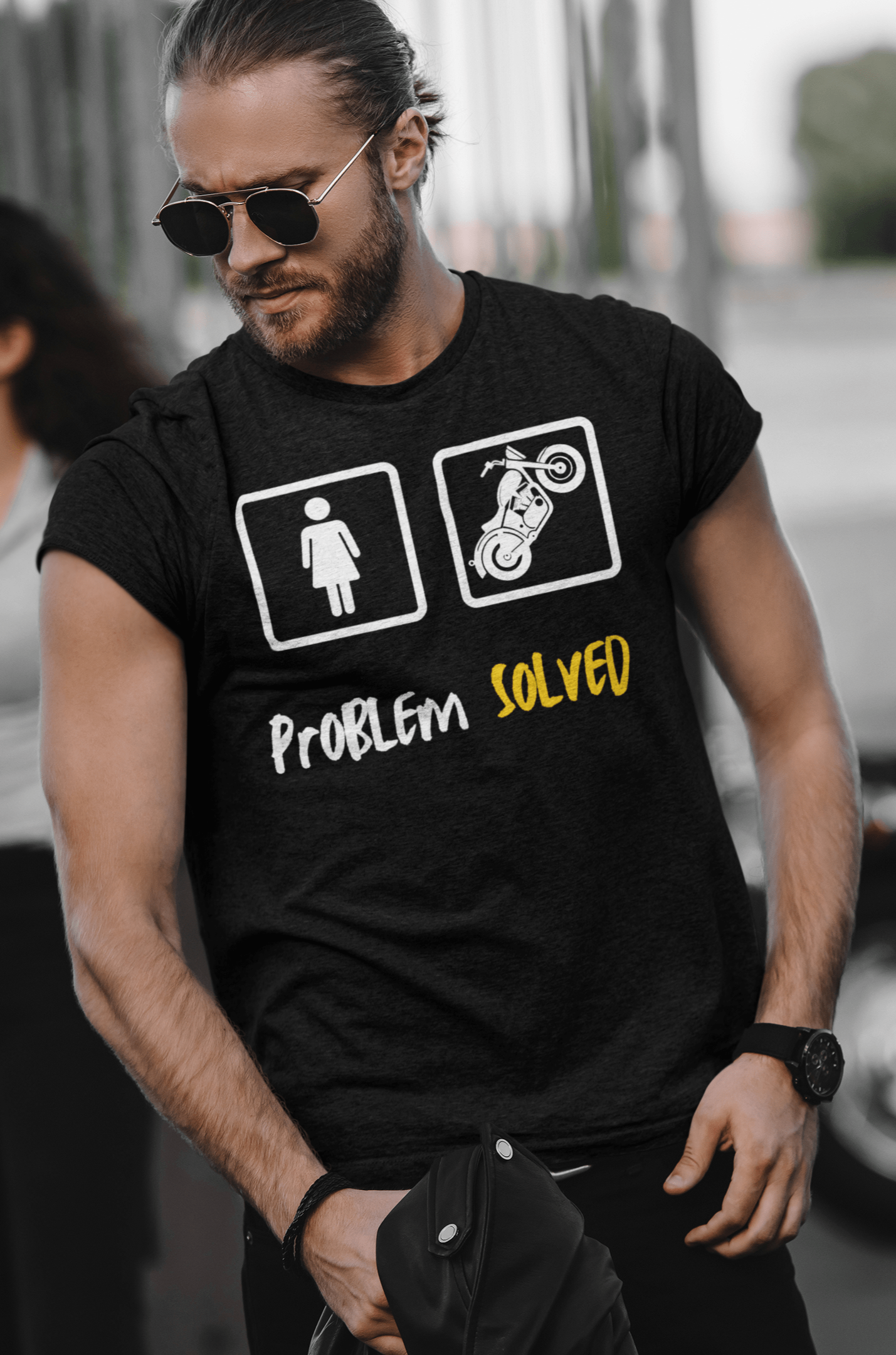 A man with tied back long hair wearing a funny biker tshirt with the words "Problem Sloved" With a Woman IN A White outlined box and a motorcycle in another outlined box.